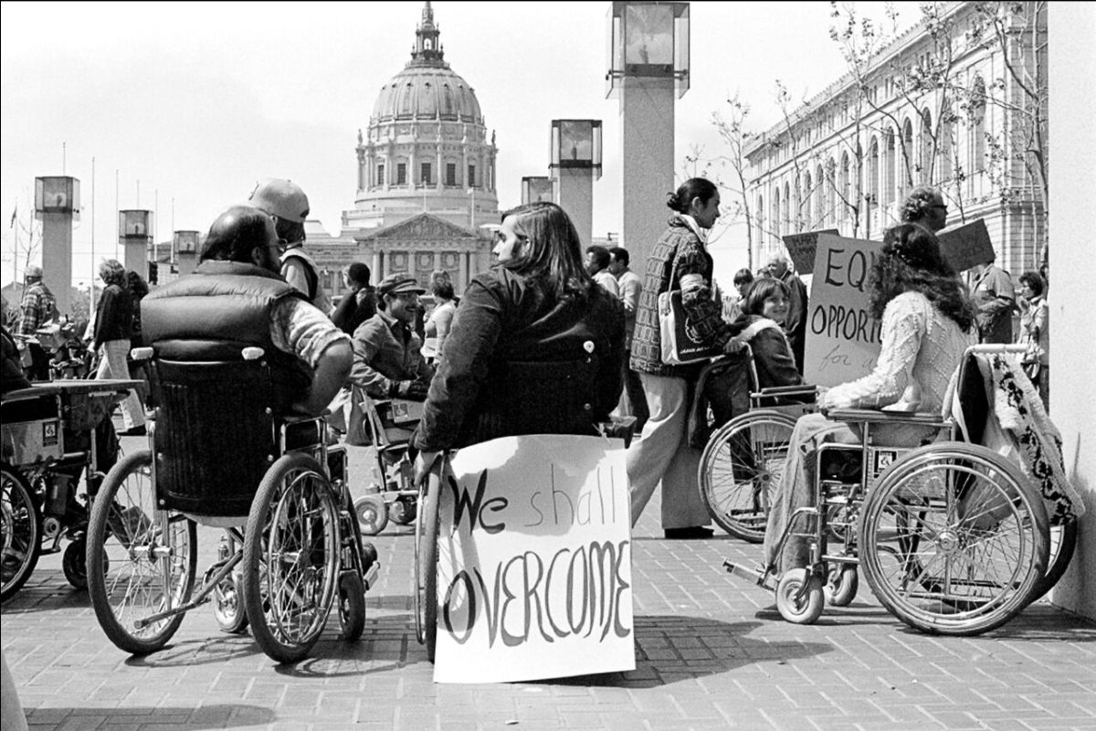A black and white photo picture of protesters in Wheelchairs in front of Capitol.