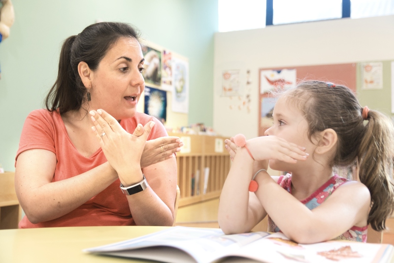 Una maestra mostrandole lenguaje de señas a su hija