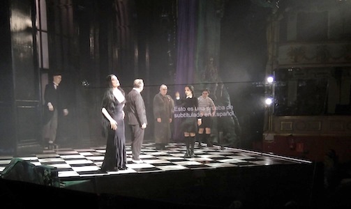 Teatro. Escena de La Familia Addams. Atril transparente con subtítulos: 