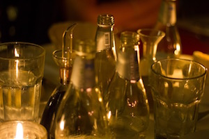 Glasses and bottles dimly lit by candles