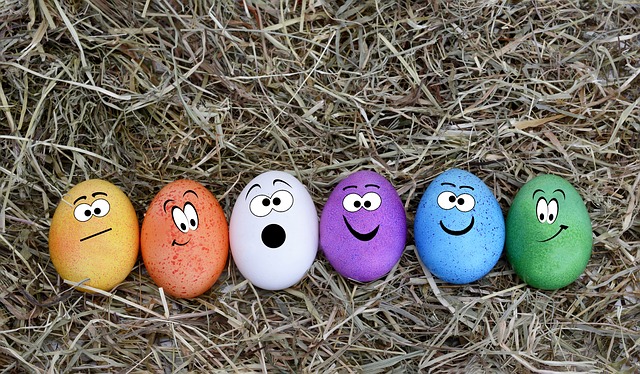 On dead grass, row of colored Easter eggs with faces painted