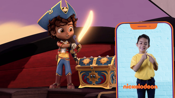 Cartoon of a pirate boy raising a sword next to a chest. On the right, on a mobile phone, a boy does sign language. In orange letters the word Nickelodeon appears at the bottom of the phone screen.