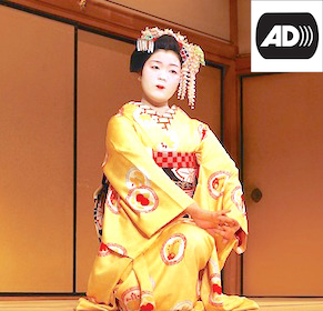 Japanese woman wearing a kimono. Her black hair is tied up. On the image, the symbol of audio description