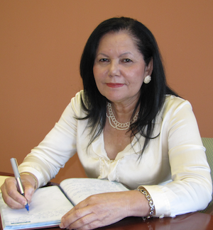 La doctora Juanita Rodriguez escribe sentada frente a una mesa 