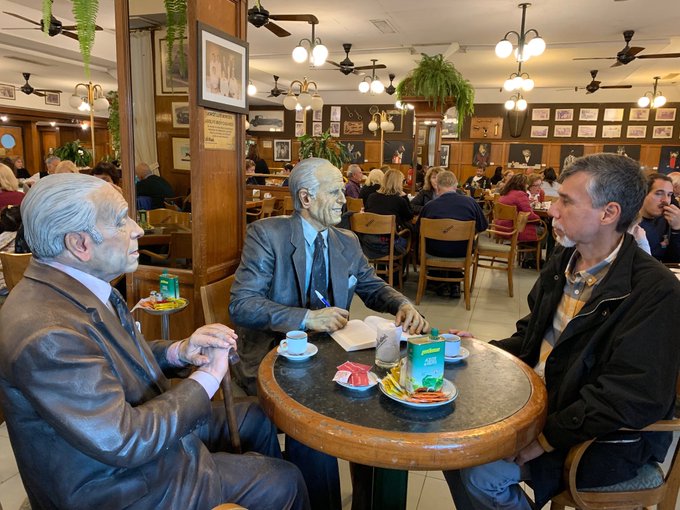 Dean having a coffee with a statue of Borges