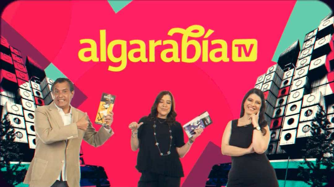 Pink background. Text in yellow: Algarabía TV. Two women and a man smile and stand below the text. The man and one of the women hold a magazine each.
