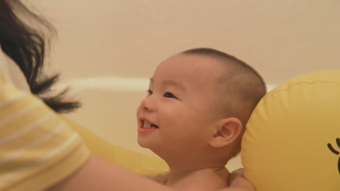 A baby smiles in a tub.