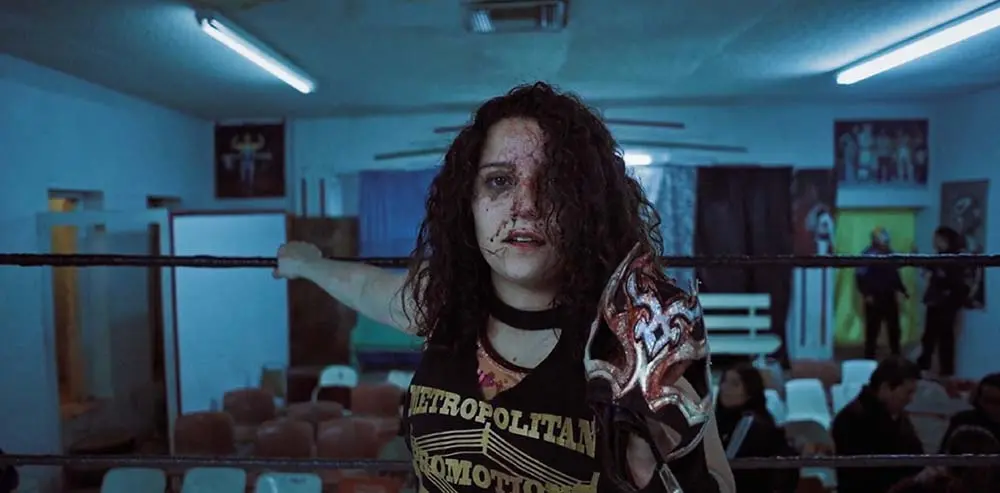 A girl in a Luchadora outfit covered in blood.