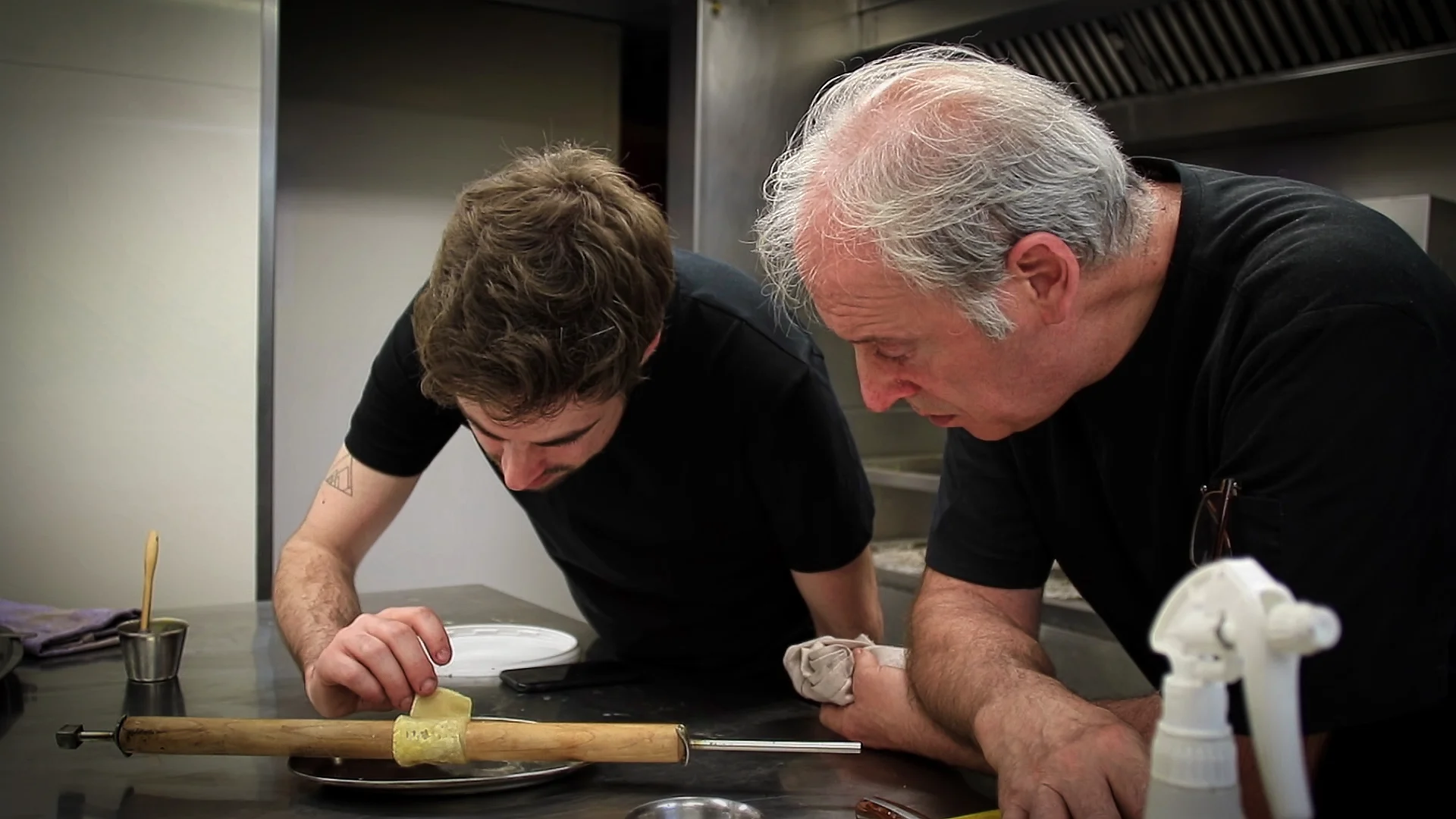 In a kitchen, two chefs look at a pastry.