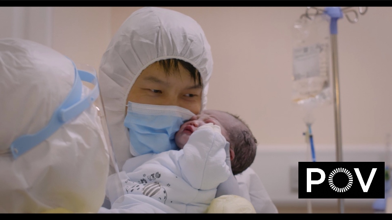 A doctor in protective gear holds a newborn