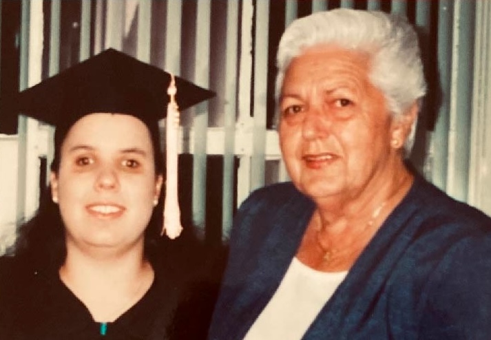 Judy, in her graduation gown, stands next to her grandmother.