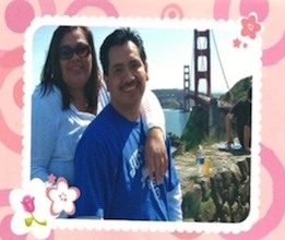 Outdoors. Myrna and her husband smile. Golden Gate bridge in the background
